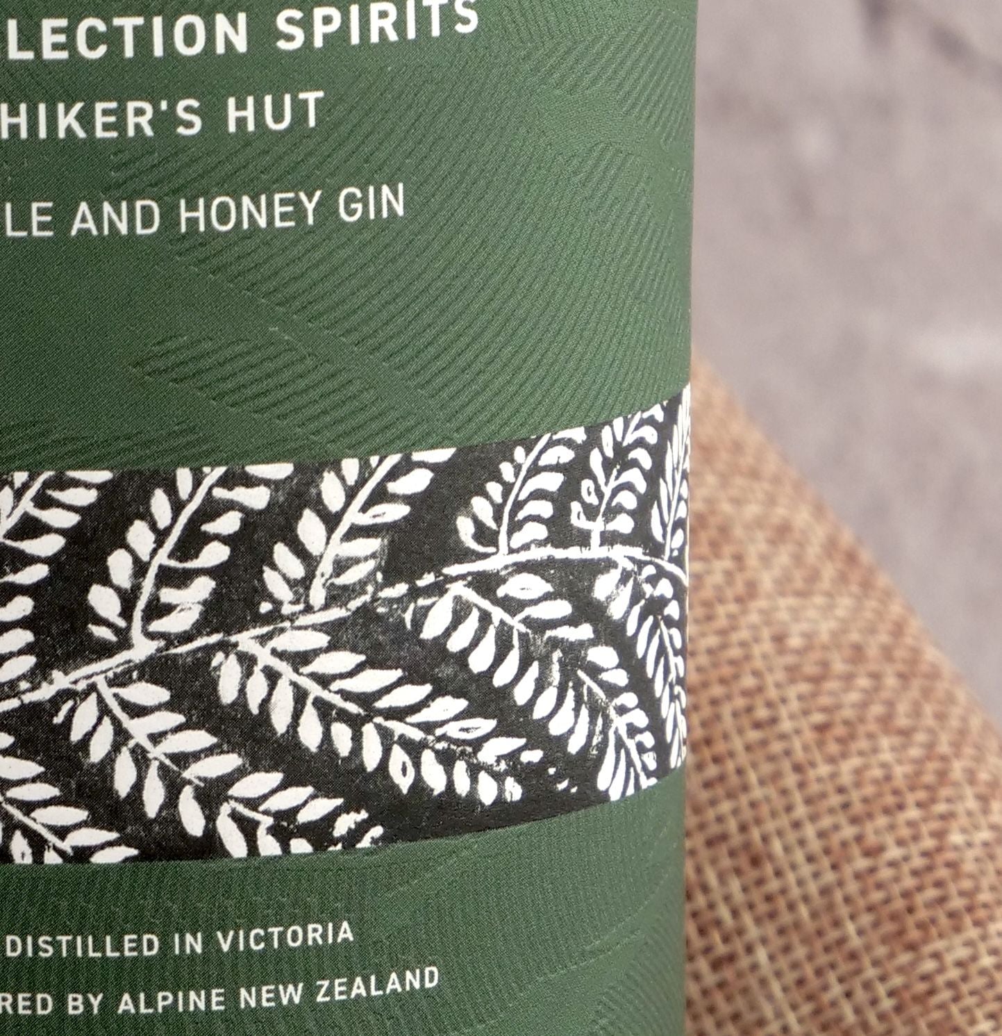 Green bottle label with white text and leaf pattern on a textured surface